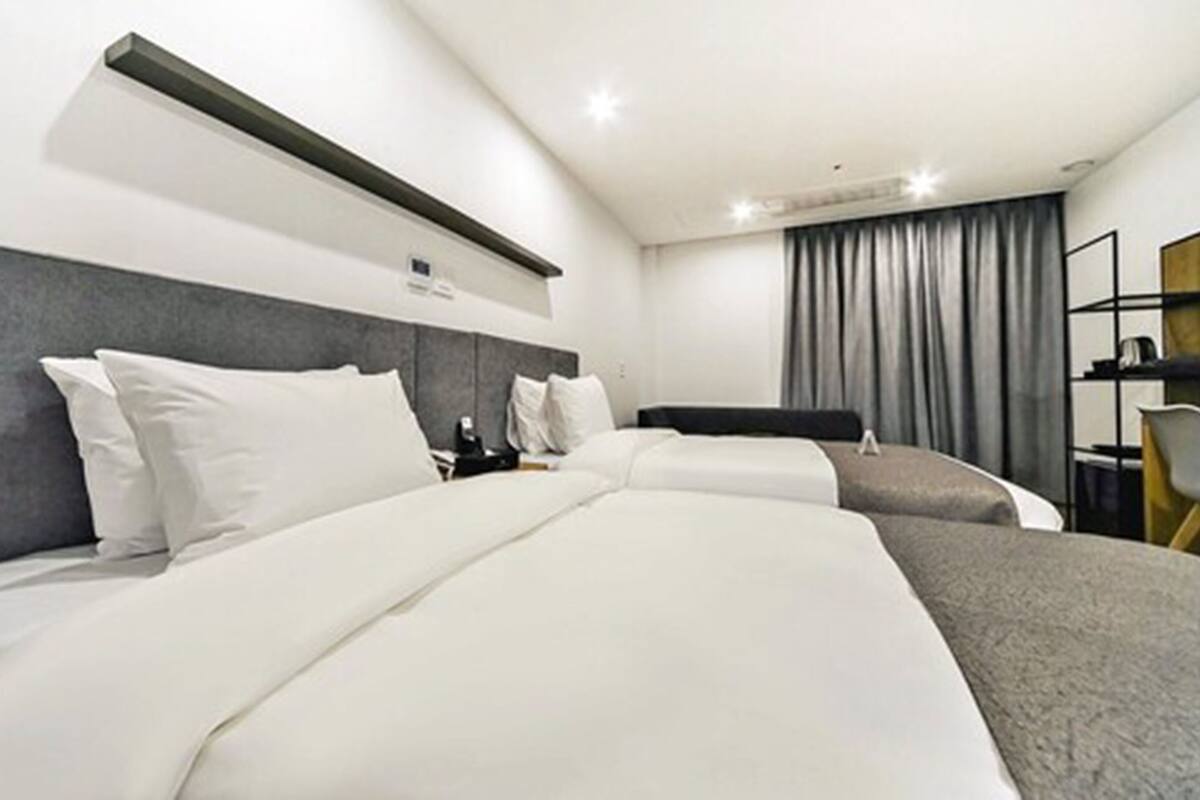 Habitación de hotel con dos camas, un escritorio y una silla.