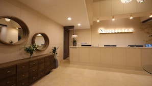 A reception area with a wooden console, two large mirrors, a potted plant, and a sign that reads "NOBLESTAY".