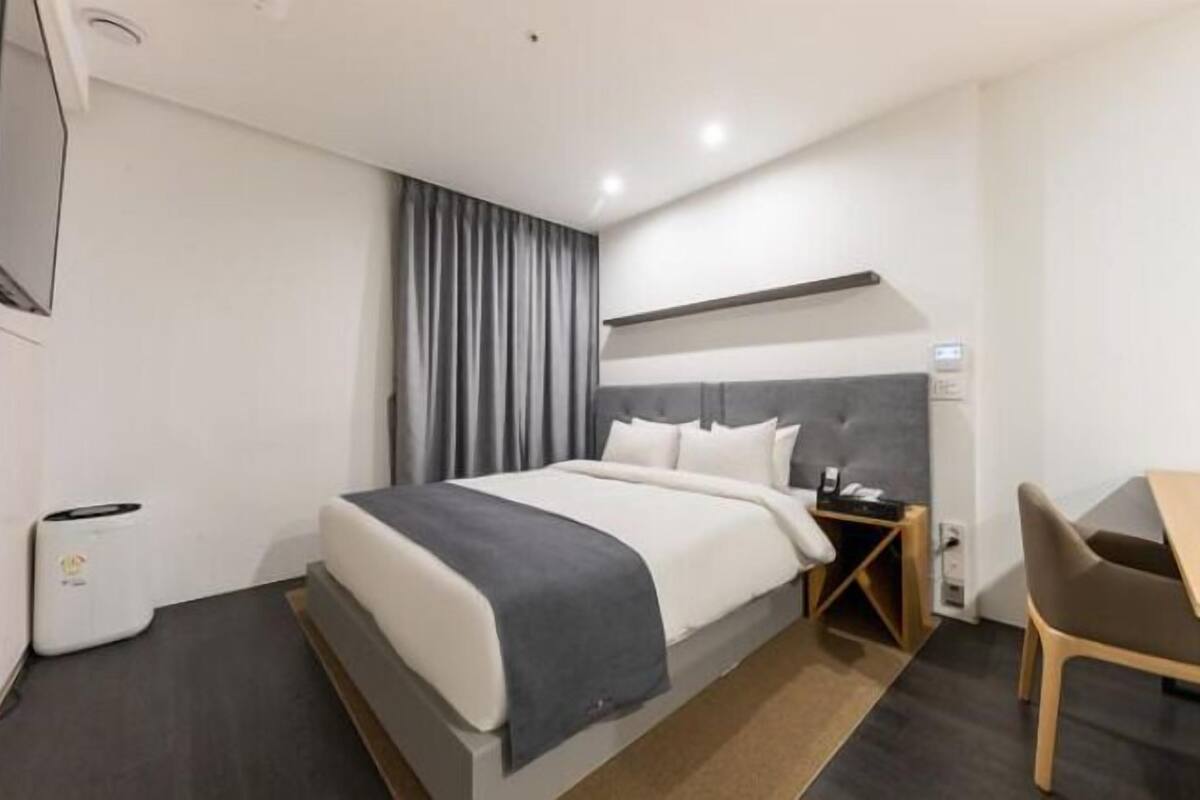 Una habitación de hotel moderna con una cama grande, un escritorio y una silla.