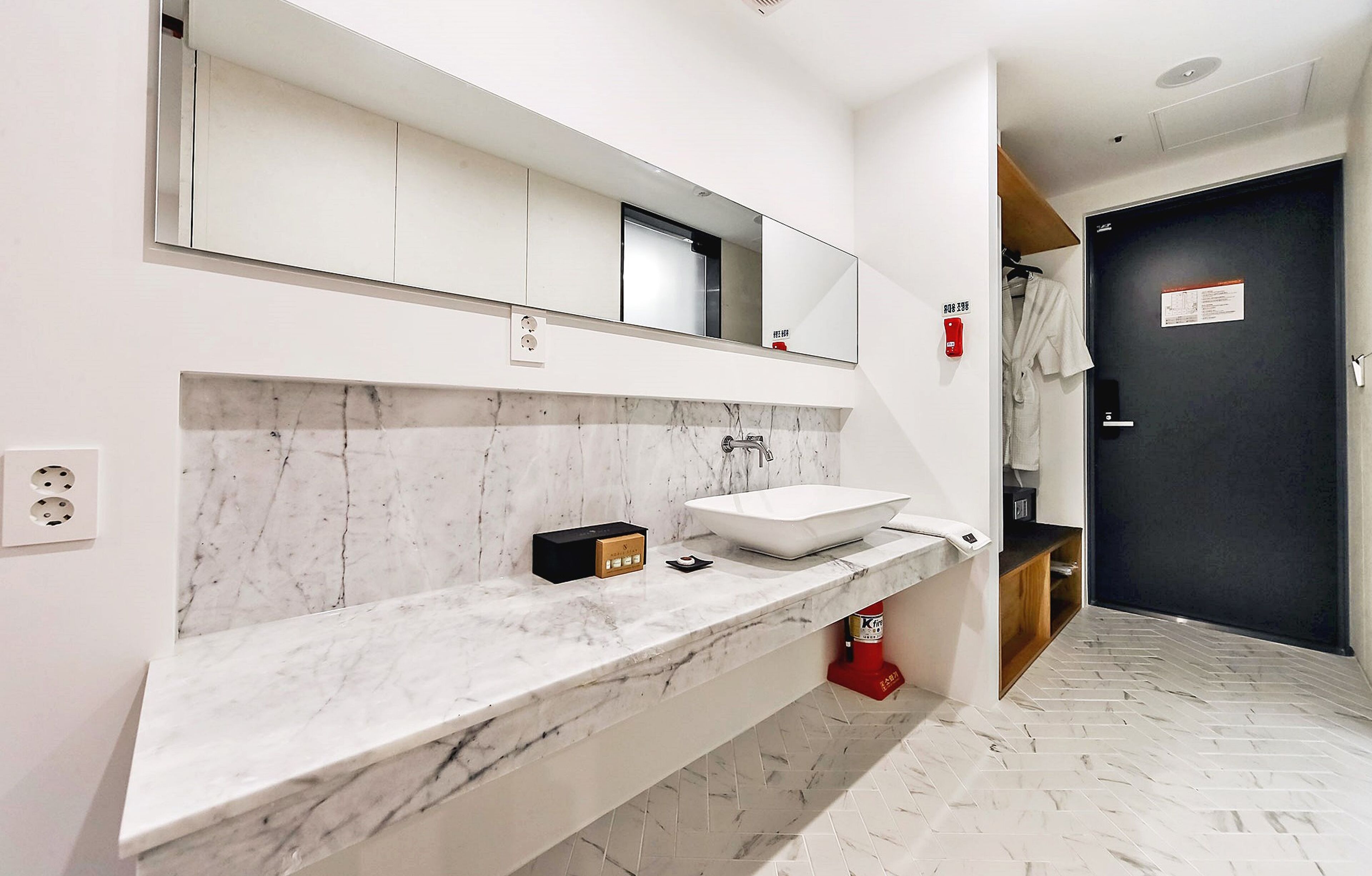 Un baño moderno con encimera de mármol, un espejo grande y lavamanos empotrado.