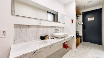 Un baño moderno con encimera de mármol, un espejo grande y lavamanos empotrado.