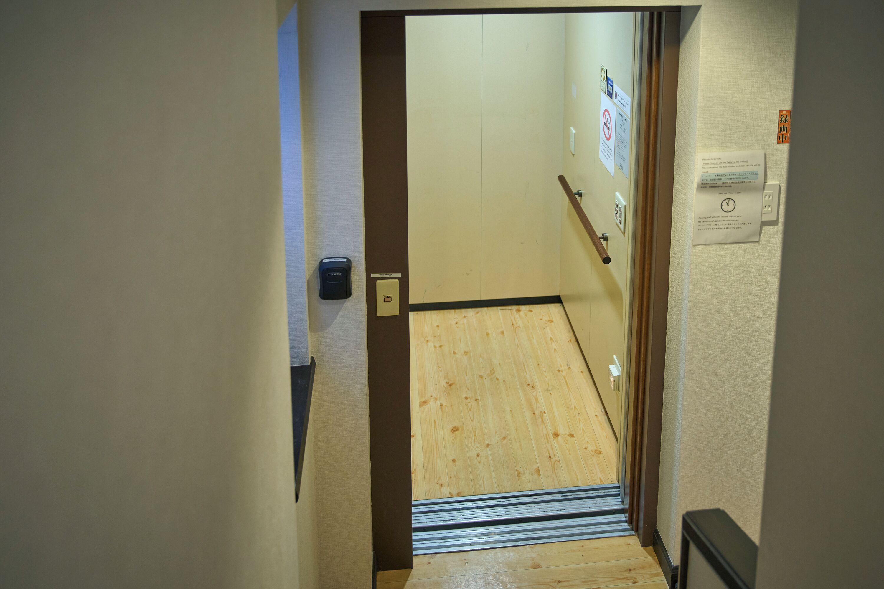 A narrow hallway with a wooden floor and a door at the end.