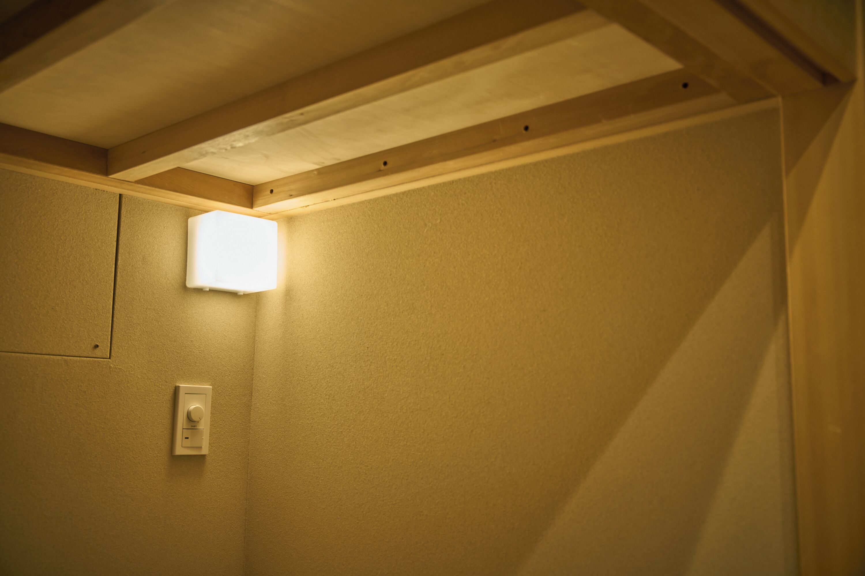Una habitación con interruptor de luz y lámpara fijada a la pared.
