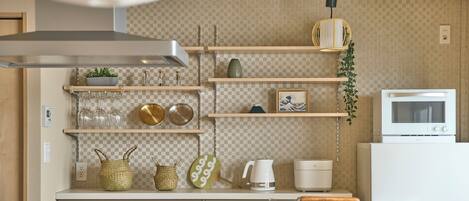 Una cocina moderna con armarios de madera, encimera blanca y diversos electrodomésticos.
