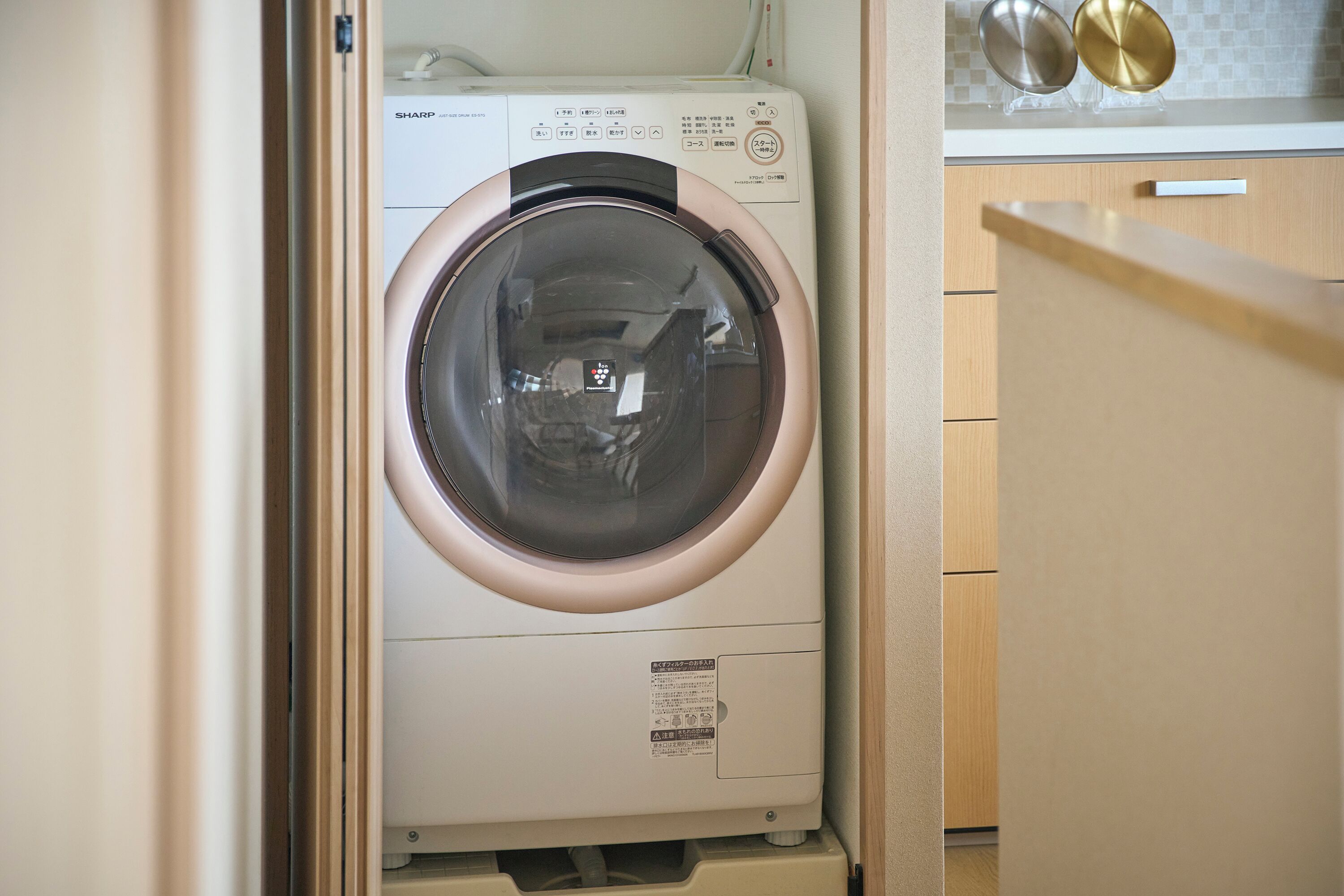 A compact washing machine with a control panel, located in a small laundry room with wooden cabinets.