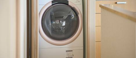 A compact washing machine with a control panel, located in a small laundry room with wooden cabinets.
