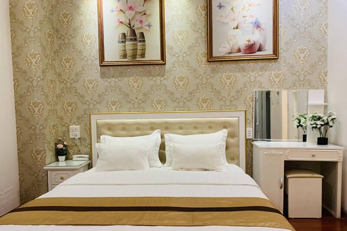 A neatly arranged hotel room with a bed, bedside table, dresser, and a mirror.