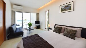 Habitación de hotel con cama, sofá, televisión y balcón con vistas.