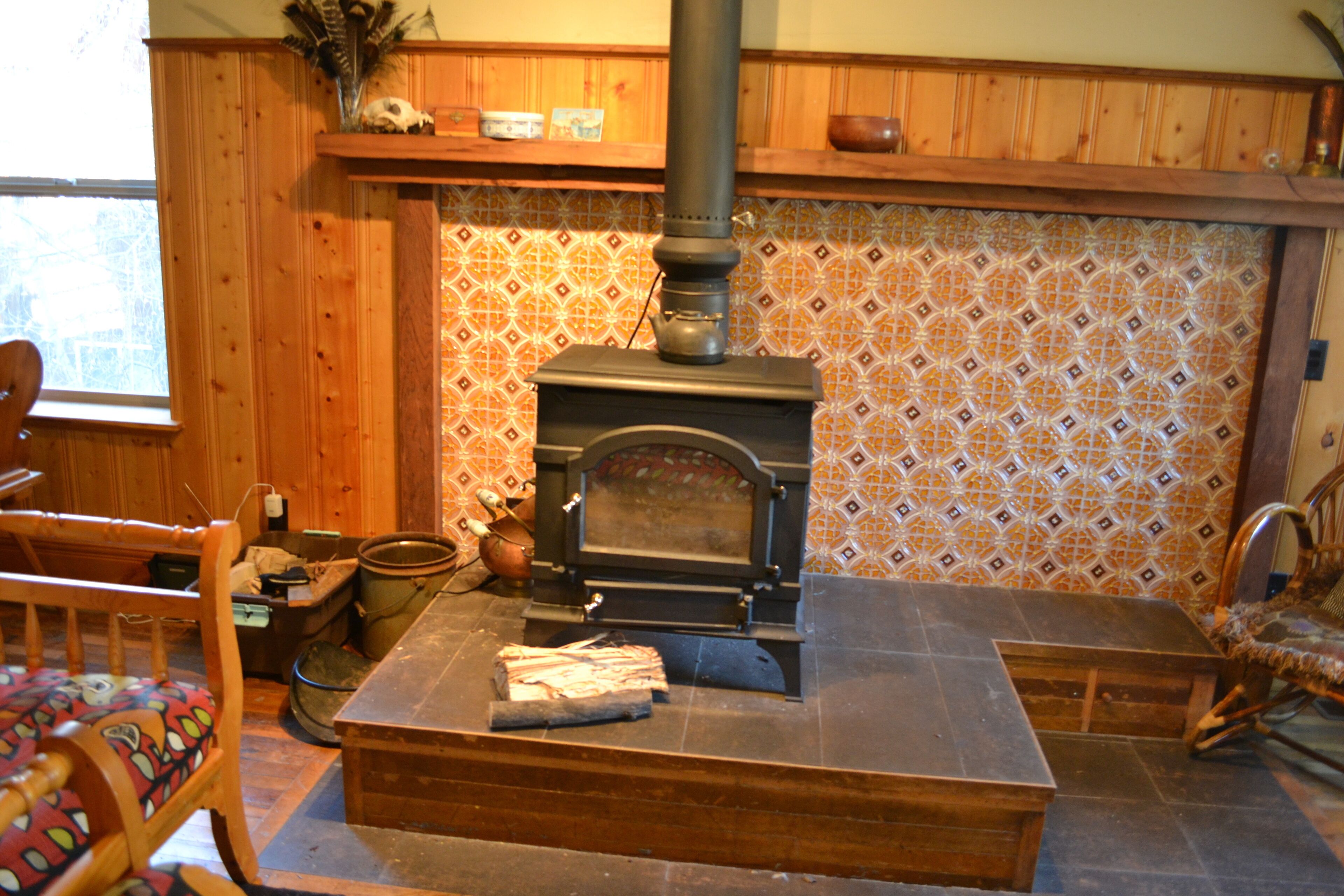 Una cucina rustica con stufa a legna, mobili in legno e zoccolo di piastrelle decorate.