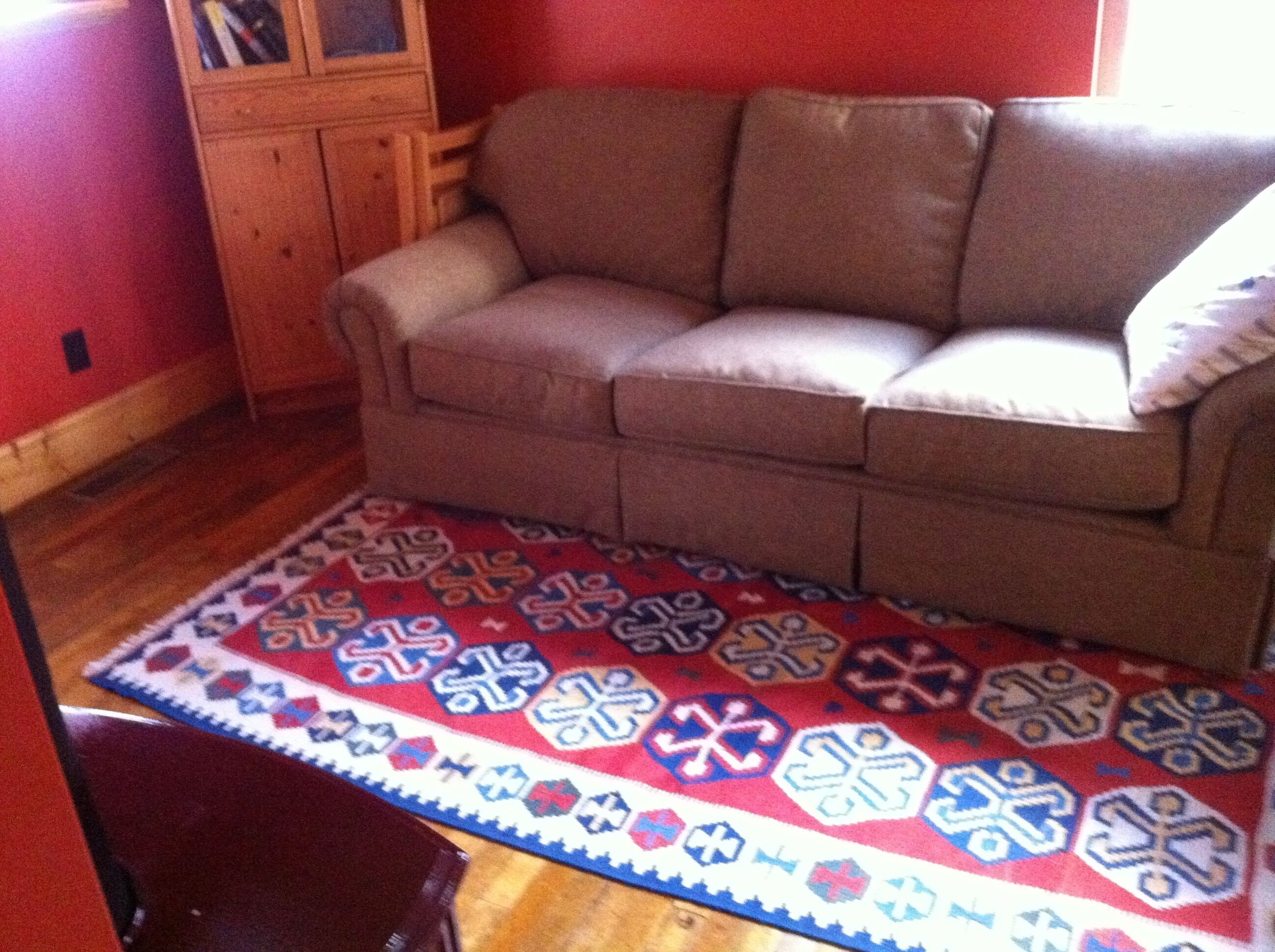 A room with a brown sofa, a patterned rug, and wooden furniture.