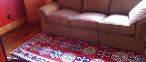 A room with a brown sofa, a patterned rug, and wooden furniture.