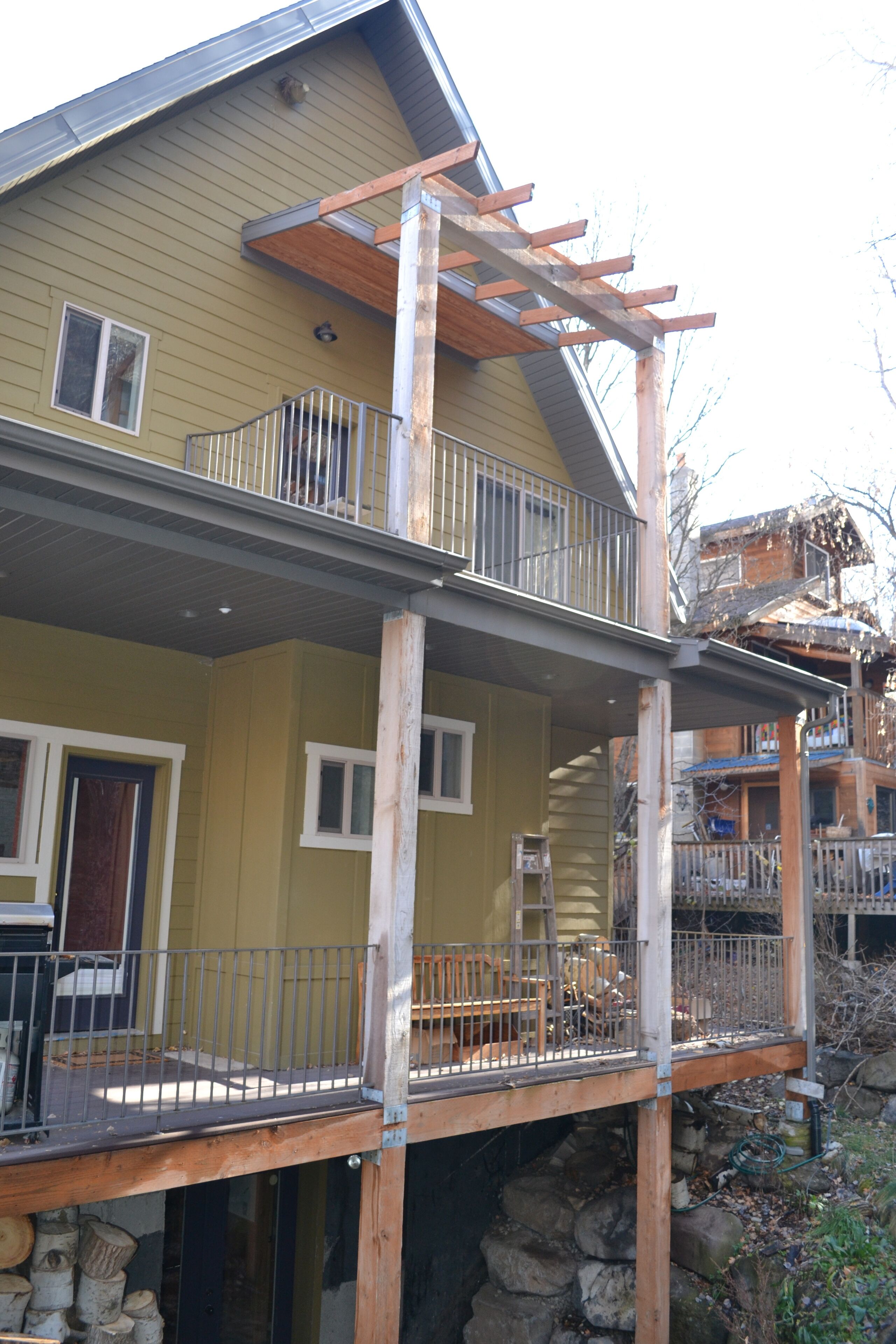 Ein zweistöckiges Haus mit Balkon, einer Holzterrasse und einem Steinfundament.