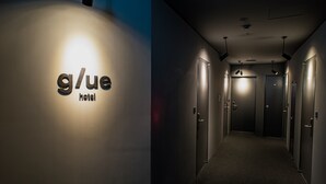 A hallway with a sign reading "g/ue hotel" and multiple doors. - glue Hotel (Seoul)