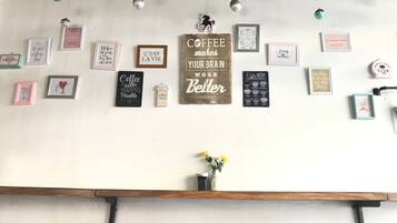 A wall with various framed motivational quotes and sayings, a coffee menu sign, and a small vase with flowers.