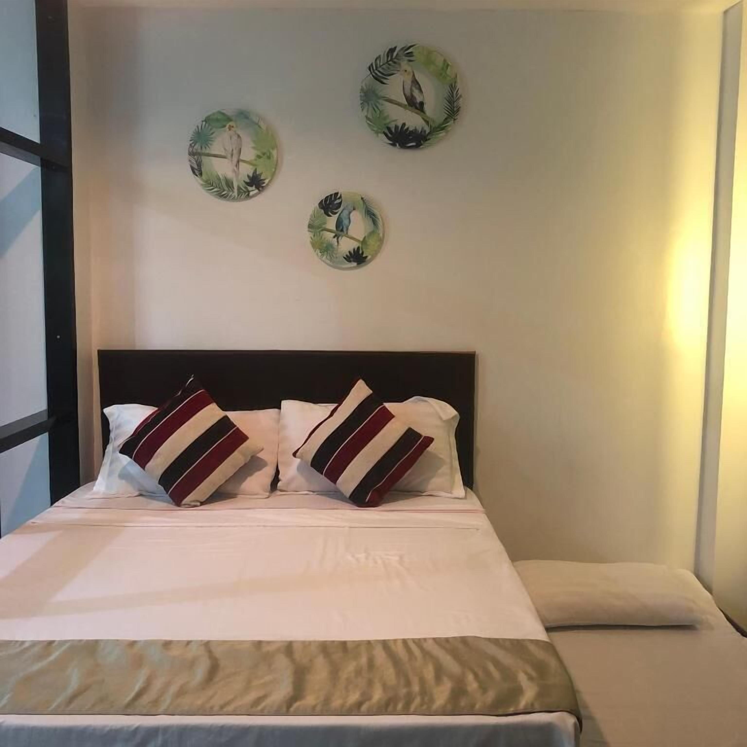 A bed with white bedding and striped pillows, a dark headboard, and three circular wall decorations with birds and foliage.