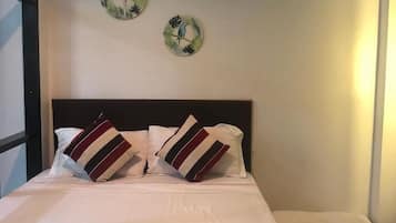 A bed with white bedding and striped pillows, a dark headboard, and three circular wall decorations with birds and foliage.