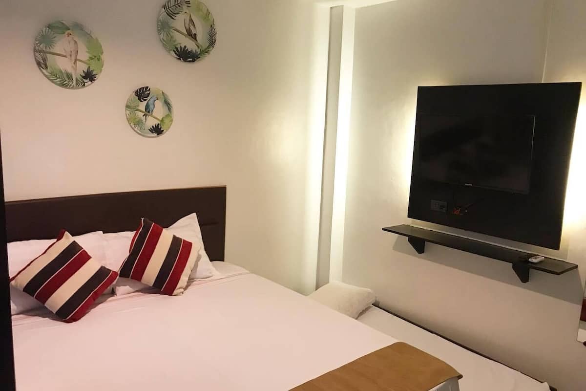Une chambre d’hôtel avec un lit, un téléviseur fixé au mur et trois assiettes décoratives accrochées au mur.