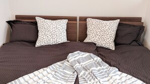 A neatly made bed with striped bedding and two patterned pillows. - Grato Terrace (Tokyo)