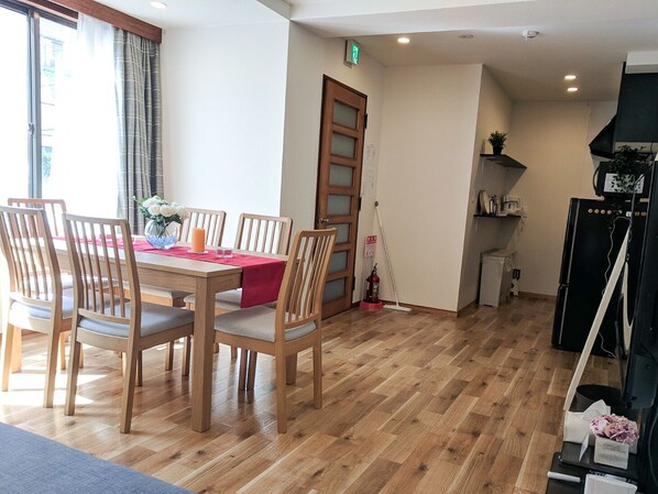 A dining area with a wooden table and chairs, a red tablecloth, and a vase with flowers. - Grato Terrace (Tokyo)