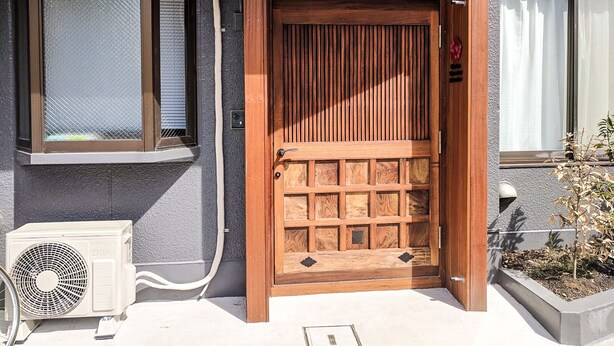 A wooden door with a grid pattern, a window with blinds, and an air conditioning unit on the left. - Grato Terrace (Tokyo)