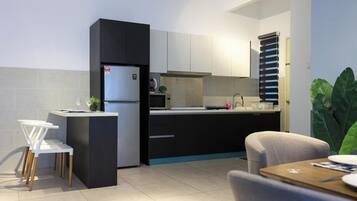 A compact kitchen with a refrigerator, microwave, and sink. There is a dining area with chairs and a table.