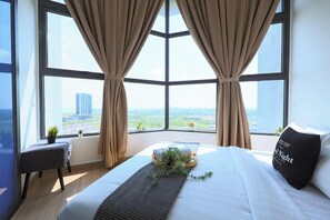 Une chambre d’hôtel avec un grand lit, une petite table de chevet, une plante en pot et une vue sur le paysage urbain à travers de grandes fenêtres.