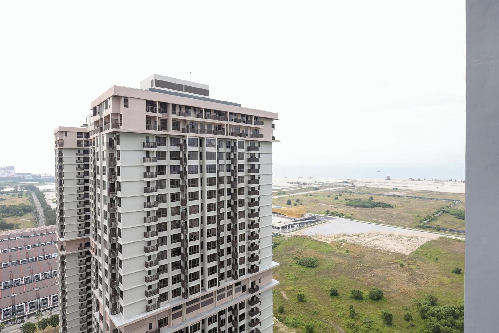 Un edifici alt amb nombroses balconades, un terrat pla i vistes cap a un paisatge costaner.