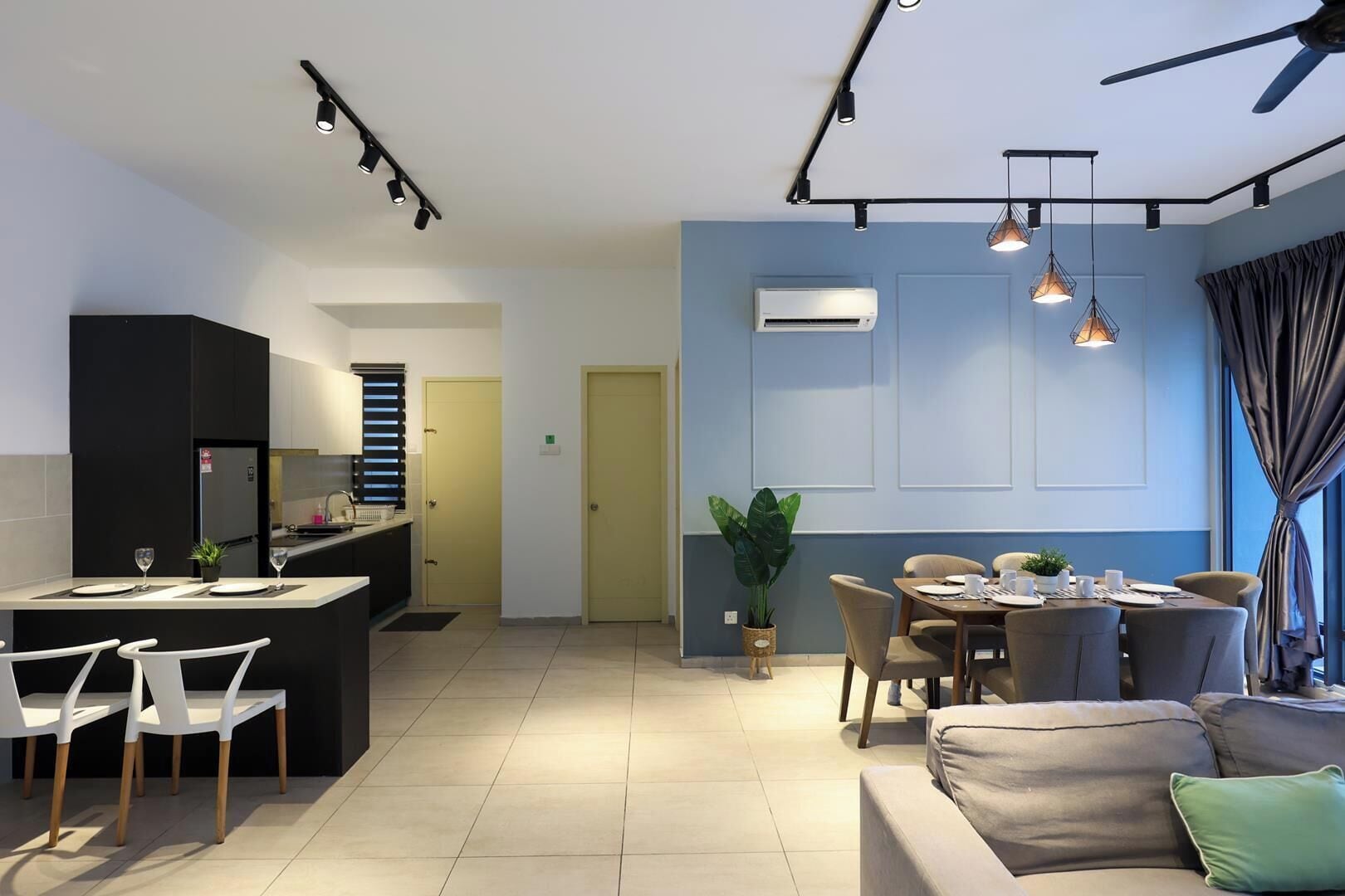 A modern kitchen with a dining area, a sofa, and a ceiling fan.