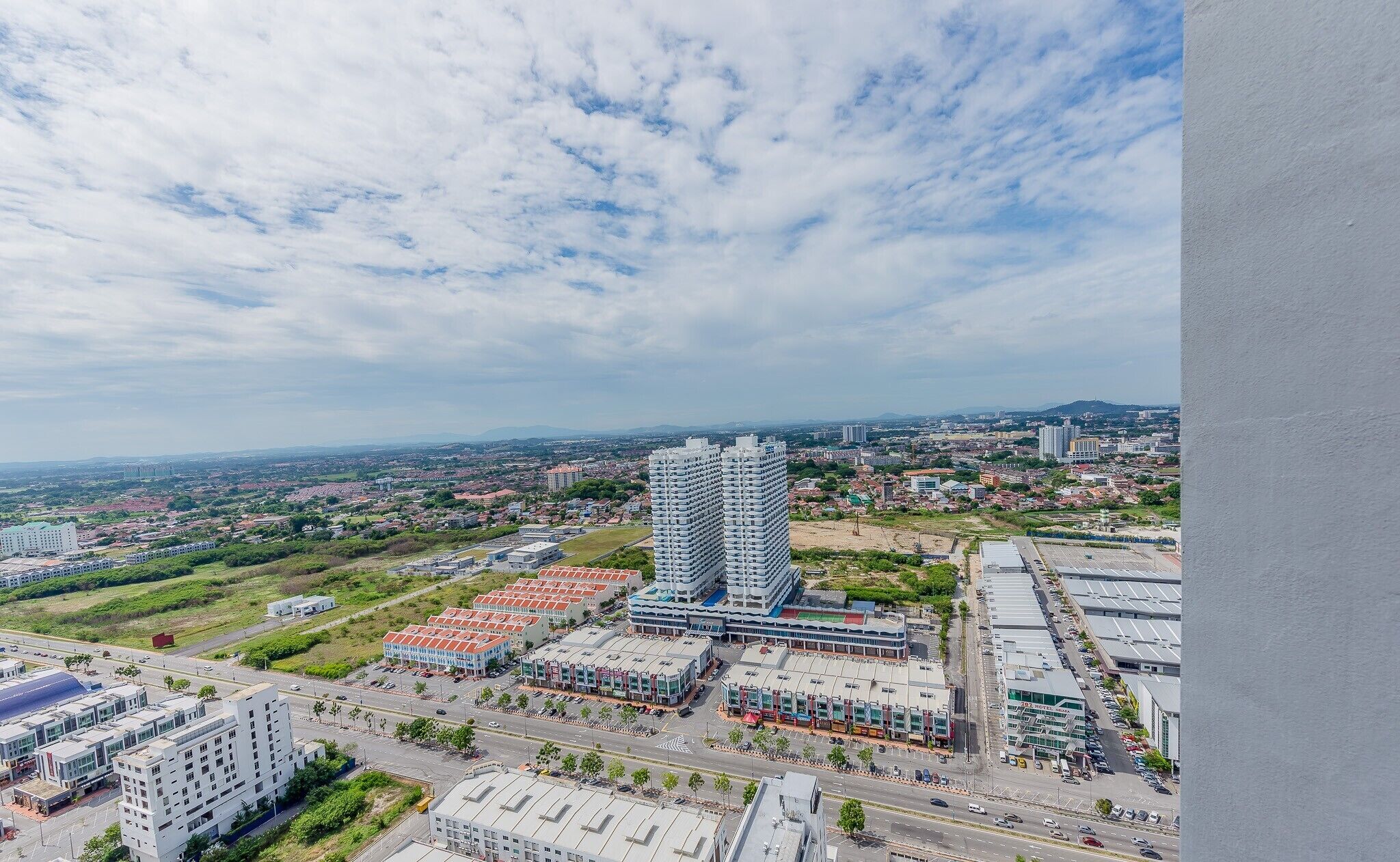 Ein hoch aufragendes Gebäude mit außergewöhnlichem architektonischen Design, umgeben von einer Mischung aus Wohn- und Geschäftshäusern, mit wolkenlosem Himmel darüber.