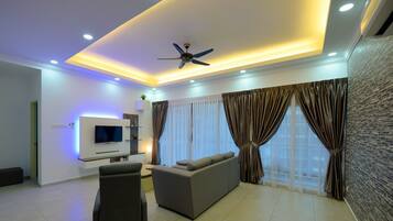 A modern living room with a flat-screen TV, a sofa, a ceiling fan, and a stone-textured wall.