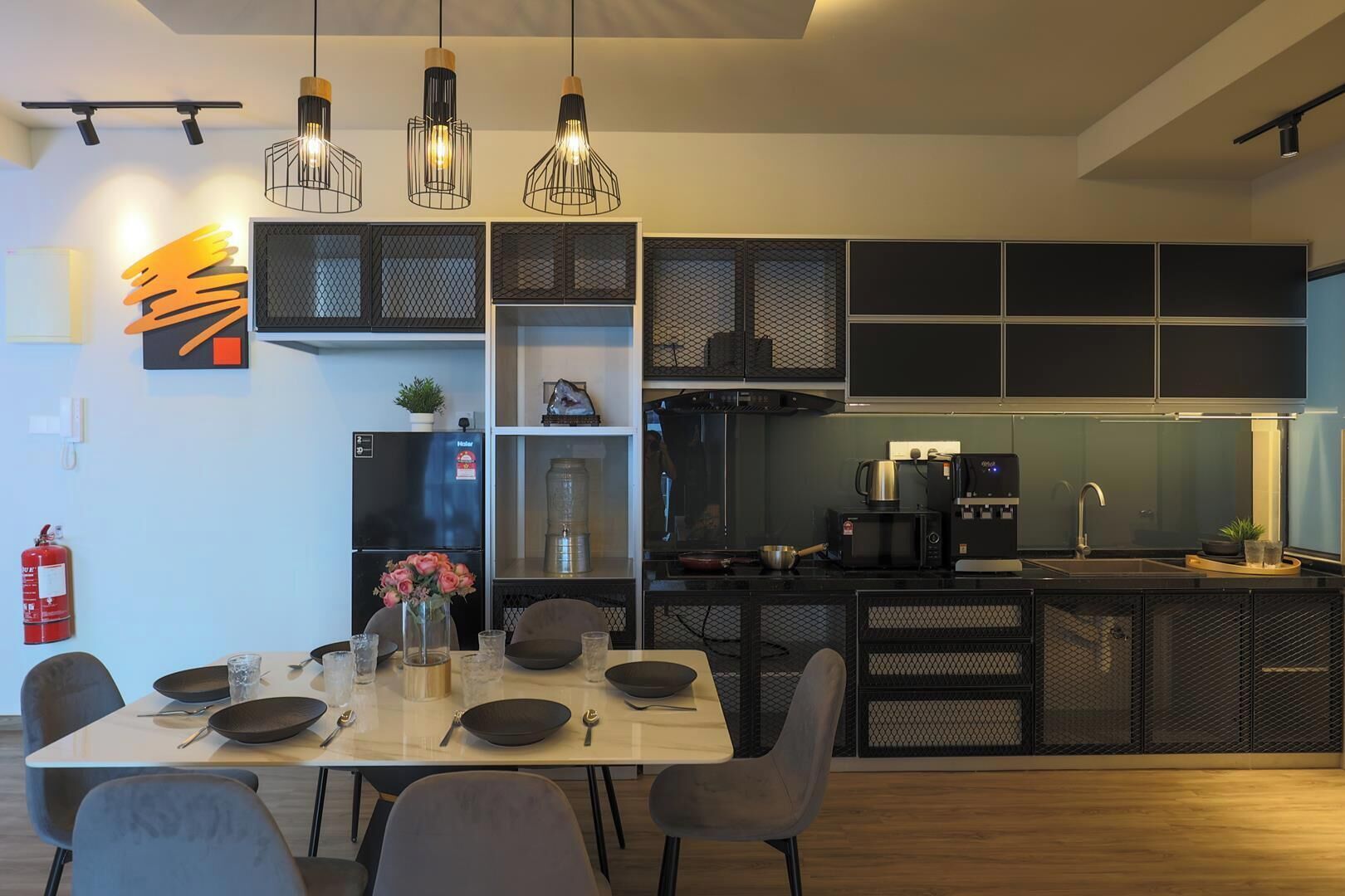 A modern kitchen with black cabinetry, a dining table with chairs, and pendant lighting.