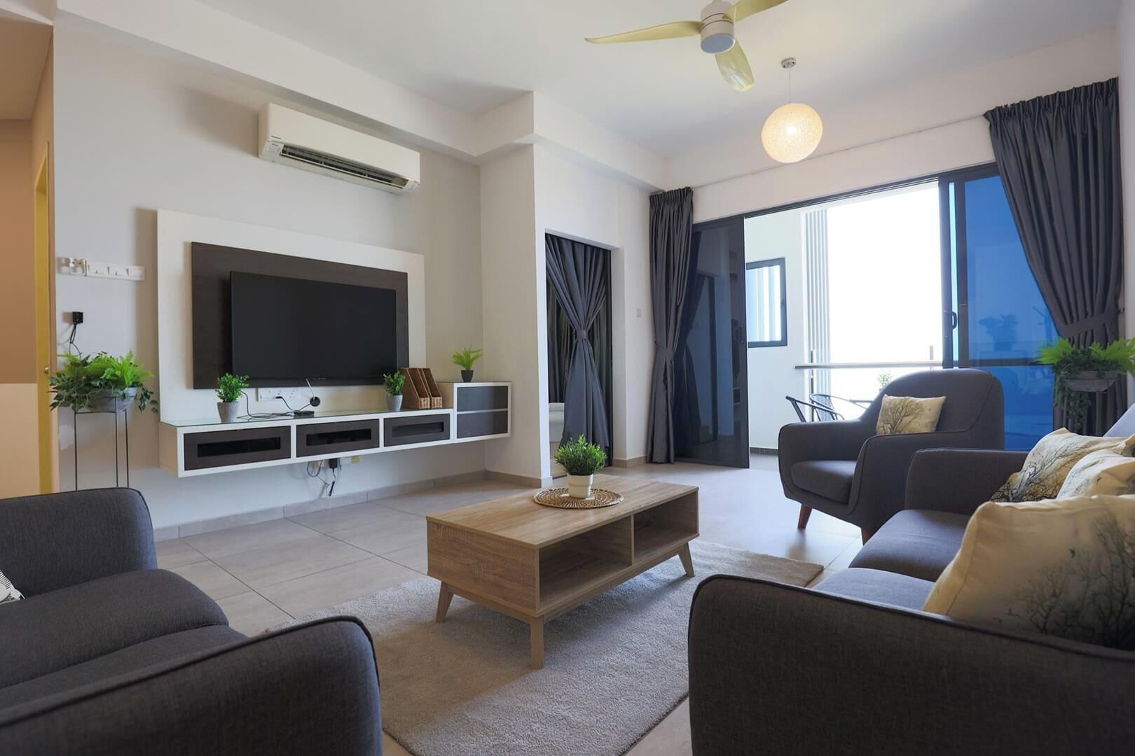 A modern living room with a flat-screen TV, a wooden coffee table, and two sofas.