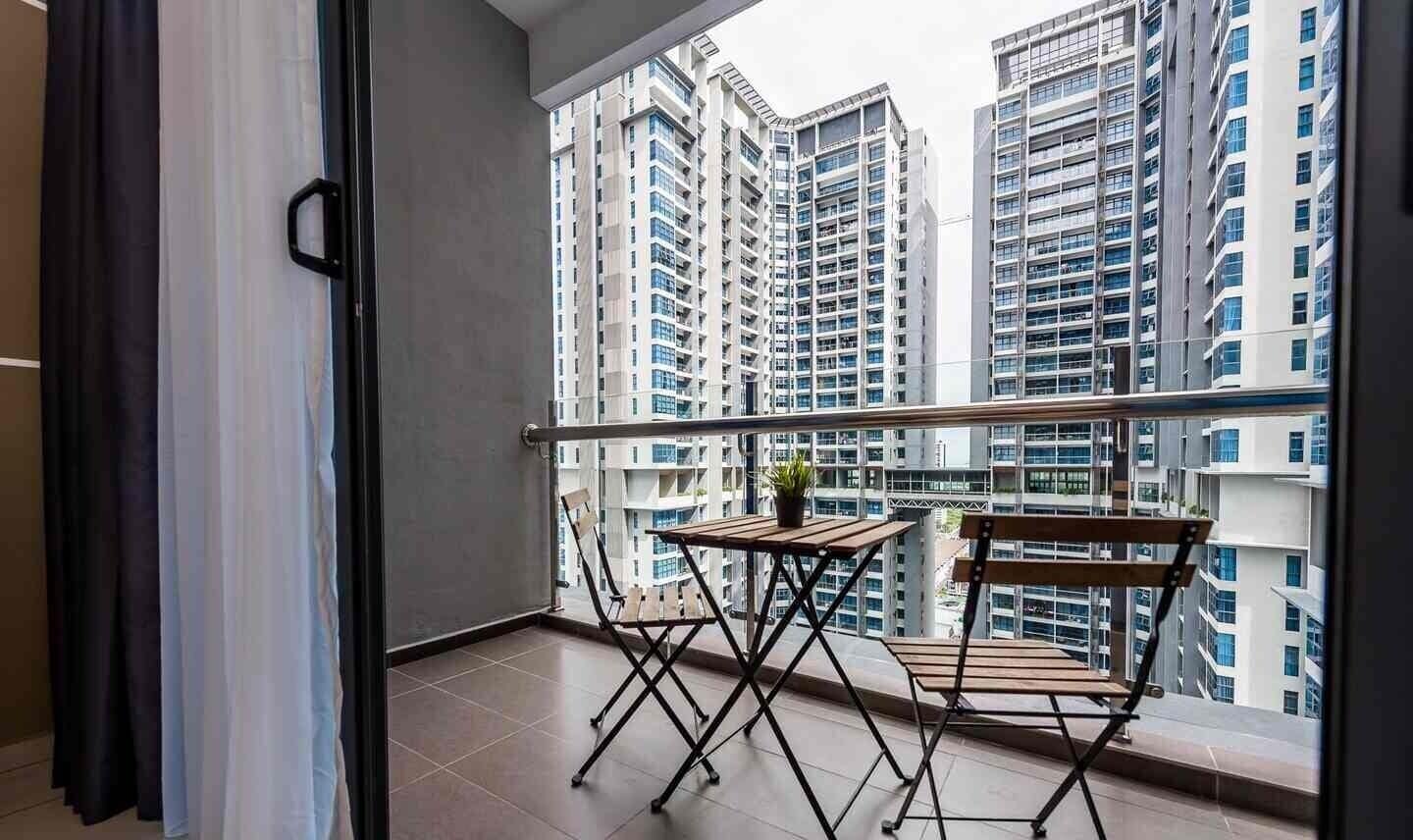 A balcony with a table and chairs, overlooking high-rise buildings.