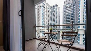 A balcony with a table and chairs, overlooking high-rise buildings.