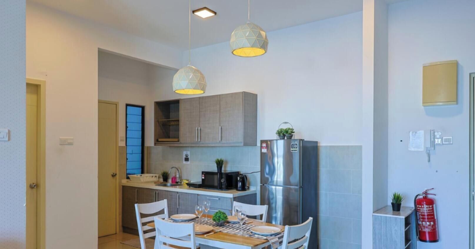 Uma cozinha compacta com área de refeições, que inclui geladeira, micro-ondas e luminárias pendentes.