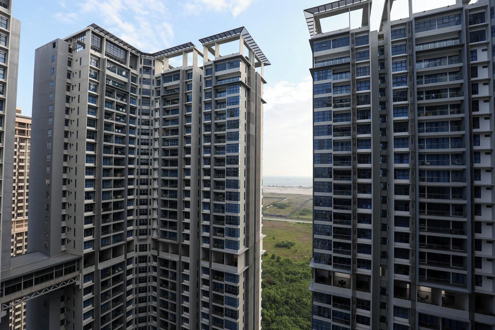 A high-rise residential building with multiple balconies and a view of a distant landscape.