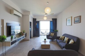 Un salon moderne doté d’un téléviseur à écran plat, d’un canapé de couleur foncée, d’une table basse et d’un ventilateur de plafond.