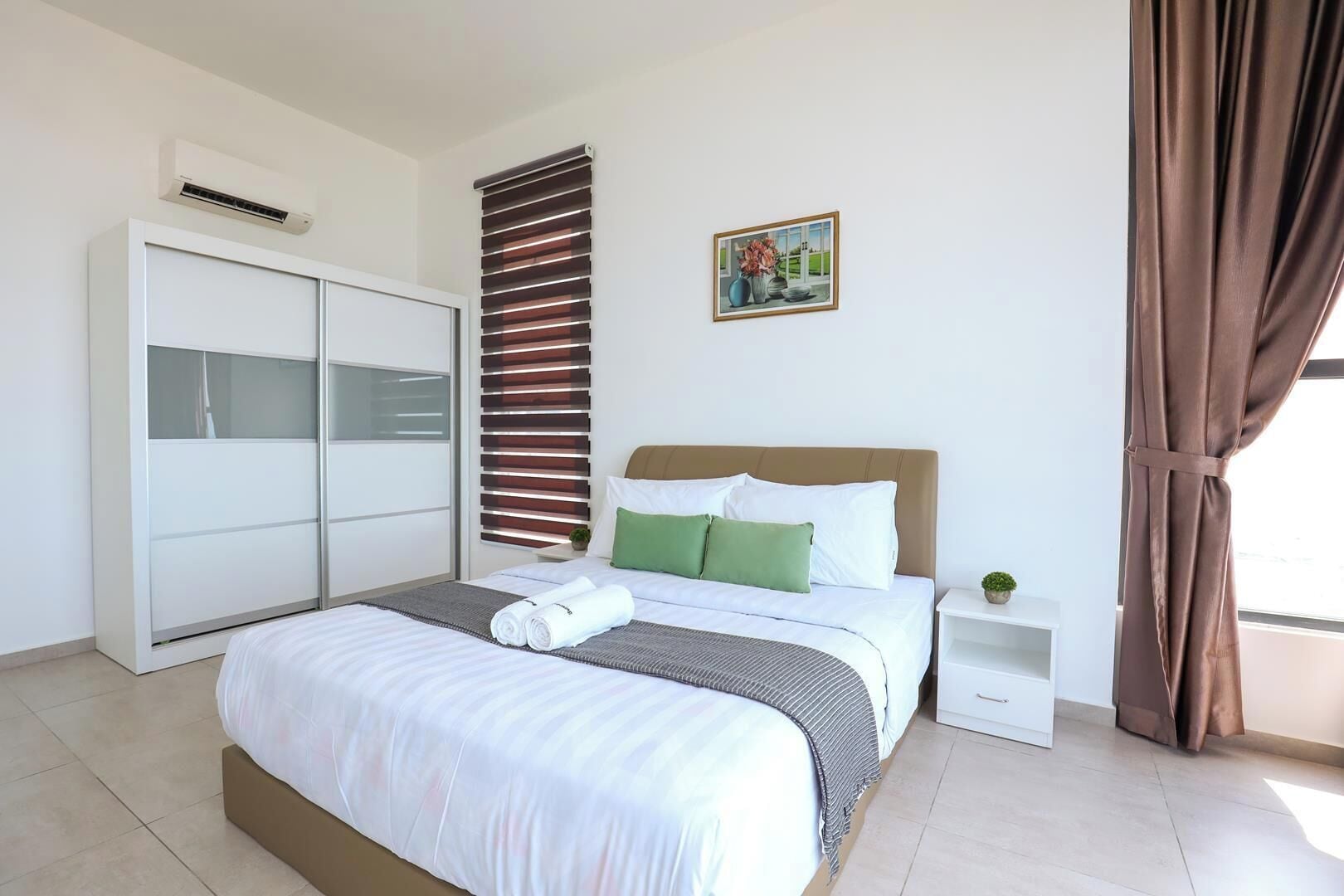 A bedroom with a bed, a wardrobe, a nightstand, a window with curtains, and a painting on the wall.