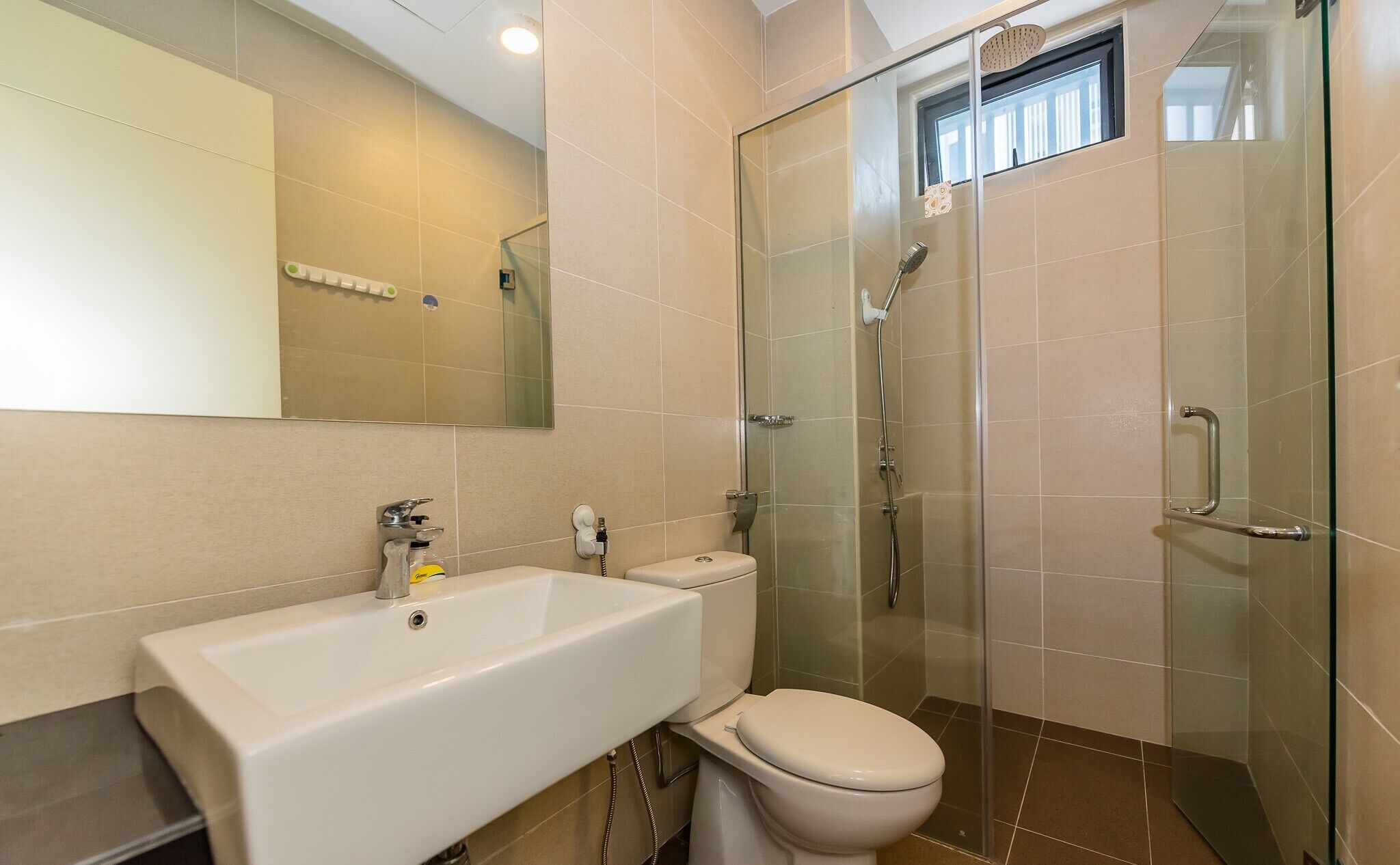 Un baño con ducha de vidrio, lavamanos blanco y retrete.