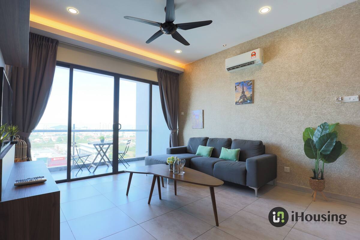 Un salon moderne avec un canapé, une table basse, un téléviseur et un balcon offrant une vue agréable.