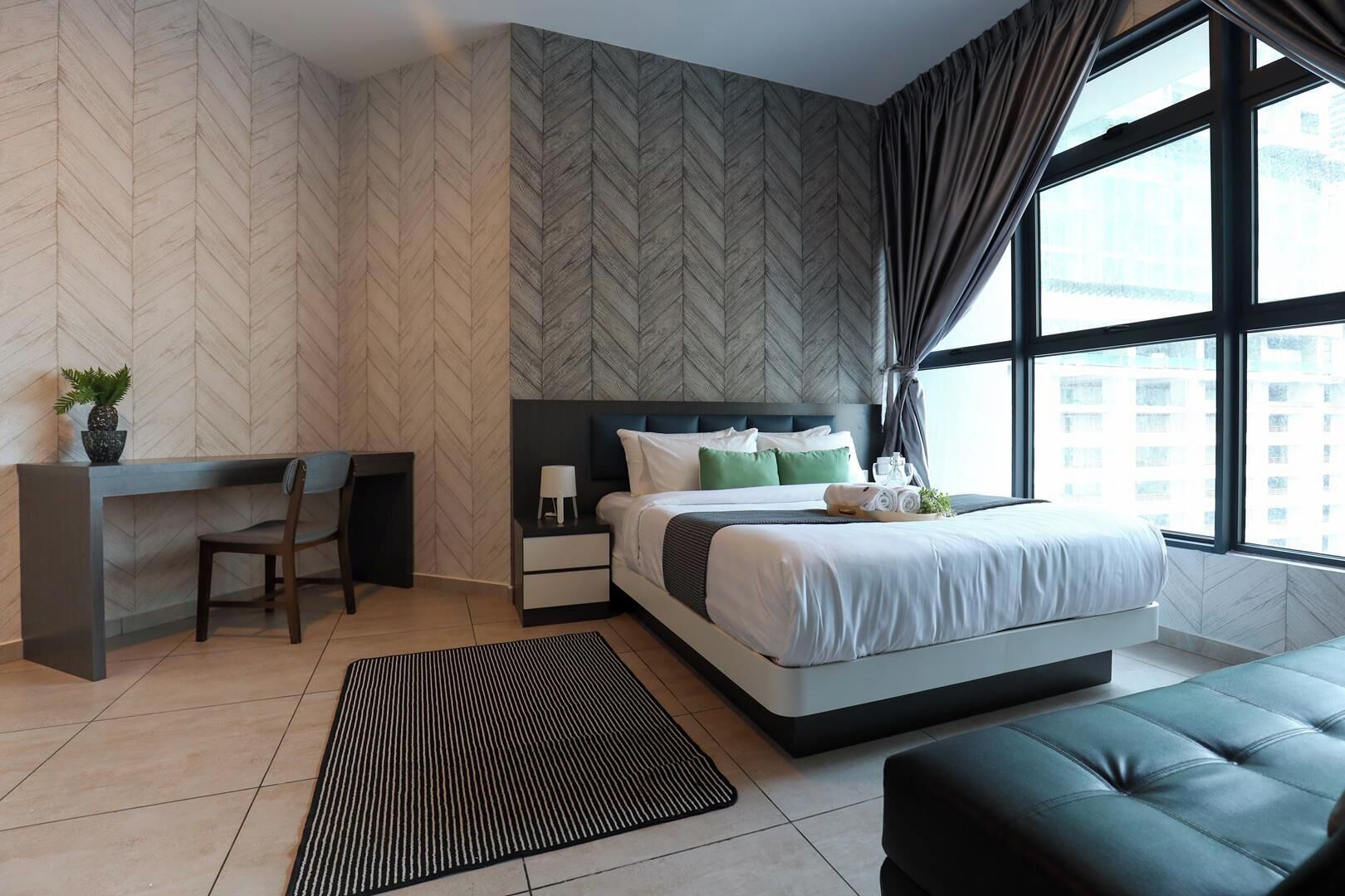 A modern bedroom with a bed, bedside table, and a desk with a chair.