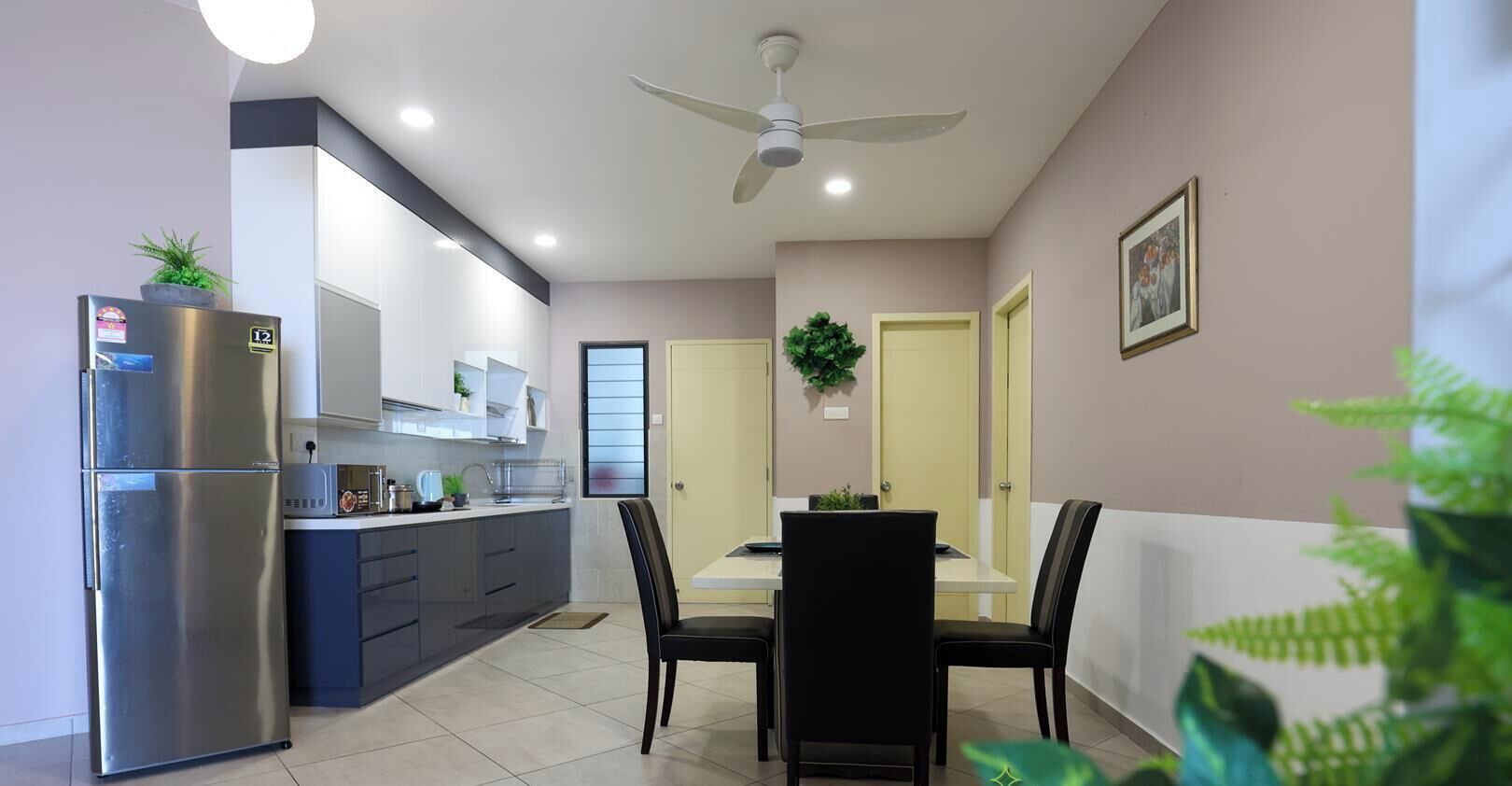 Une cuisine moderne dotée d’un réfrigérateur encastré, d’un coin repas avec une table et des chaises, et d’un ventilateur de plafond.