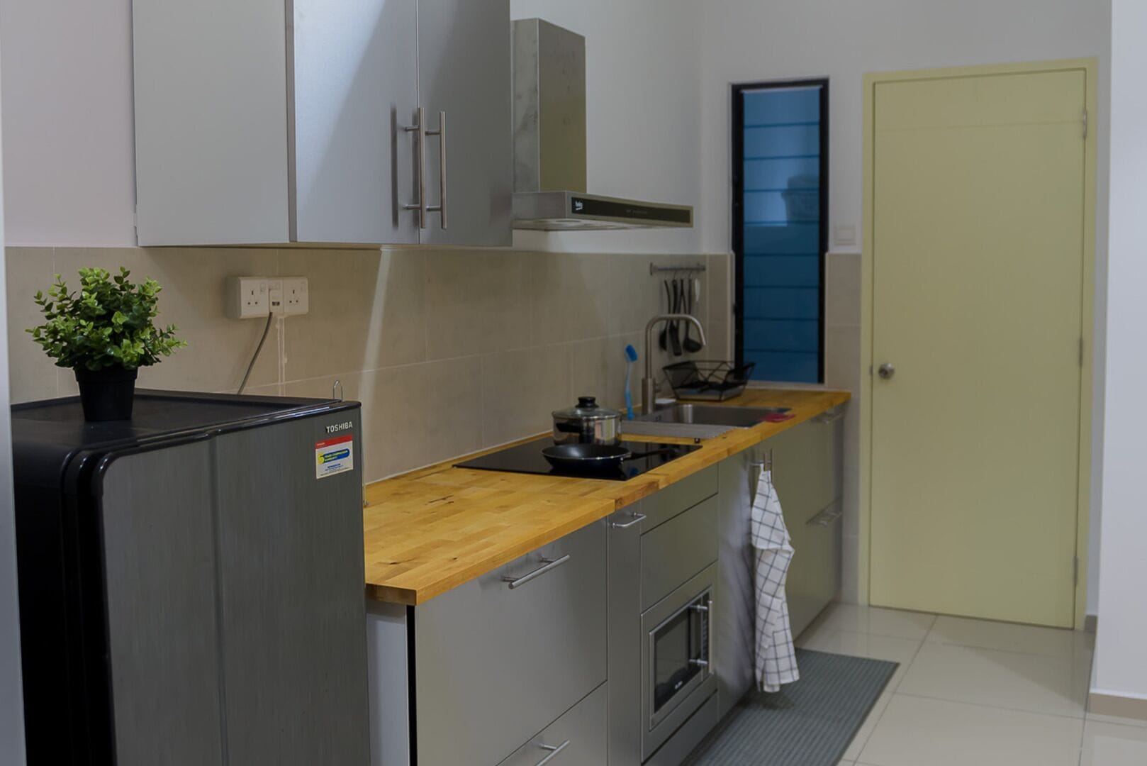 Eine kleine Küche mit Kühlschrank, Herd, Spüle und einer Arbeitsfläche.
