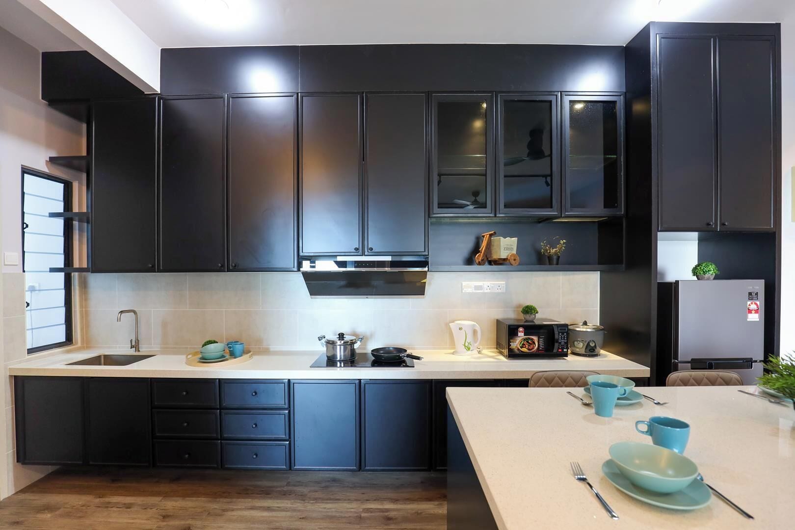 A modern kitchen with dark cabinetry, a built-in oven, and a dining area with a table set for two.