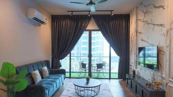 A modern living room with a sofa, a round coffee table, a ceiling fan, and a TV on the wall.