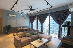 Un salon moderne avec un canapé, un coin repas et de grandes fenêtres dotées de rideaux.