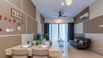 A modern living room with a sofa, a dining table with chairs, and a ceiling fan.
