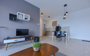 A modern living room with a flat-screen TV, a wooden coffee table, and a potted plant. - Atlantis Executive Melaka by I Housing (Malacca City)