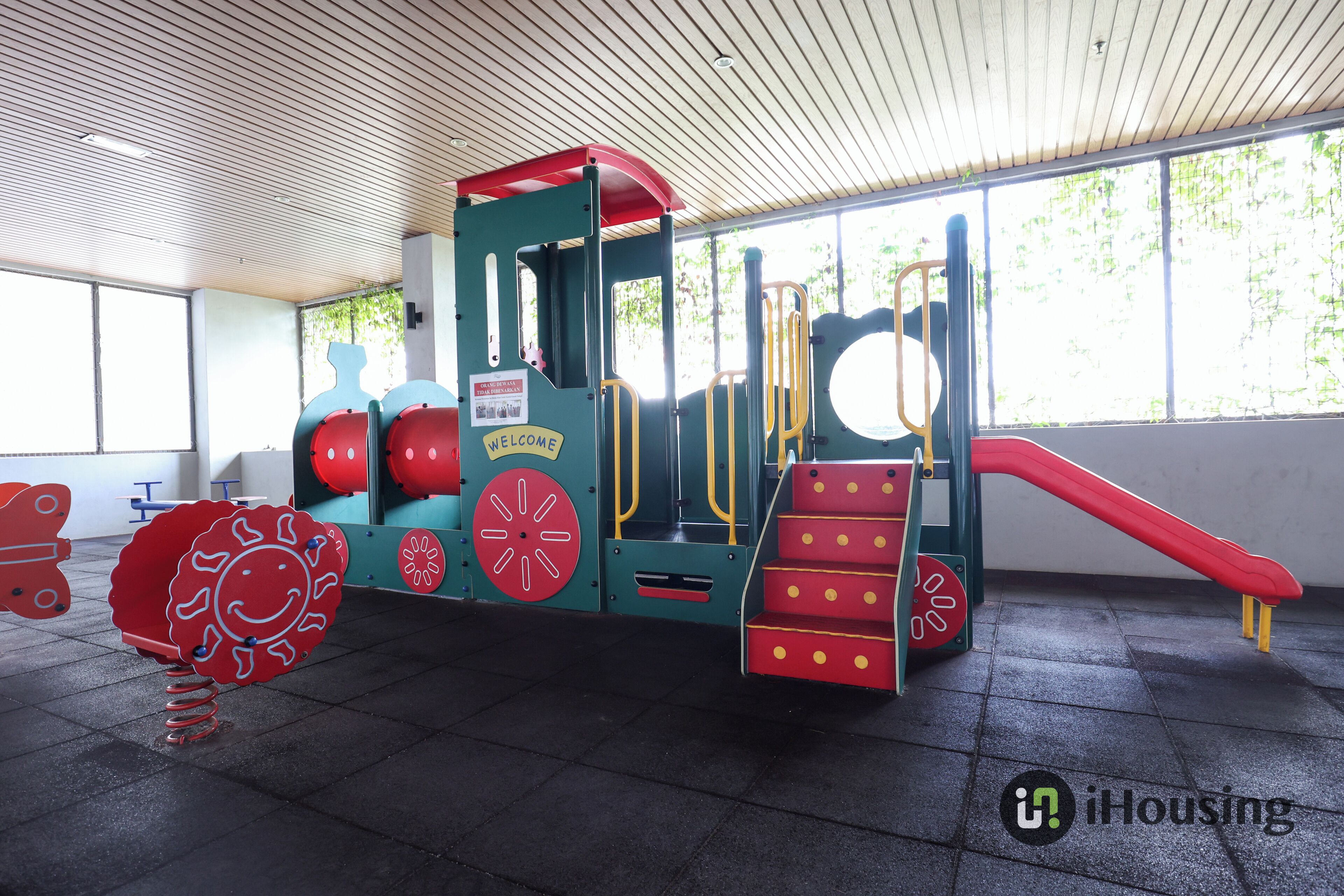 A children's play area with a slide, climbing steps, and a red and blue play structure.