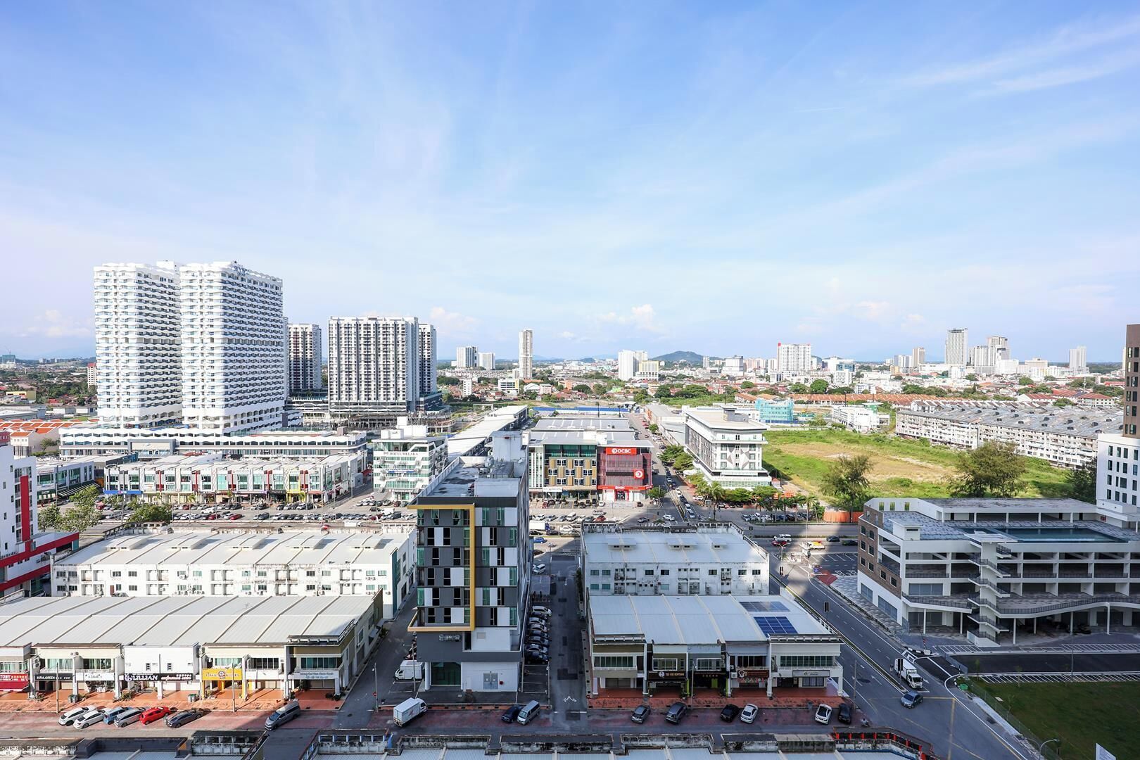 A cityscape with high-rise buildings, a central commercial area with shops, and a parking lot.